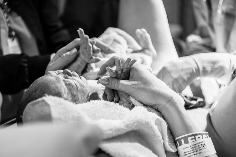 mom holding baby's hands right after she is born