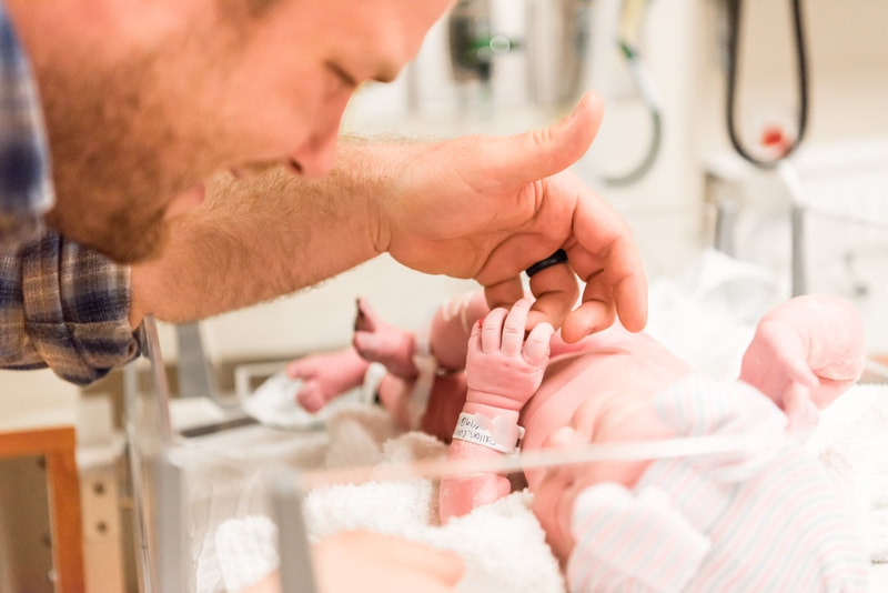 New dad touching baby's fingers for the first time in hospital