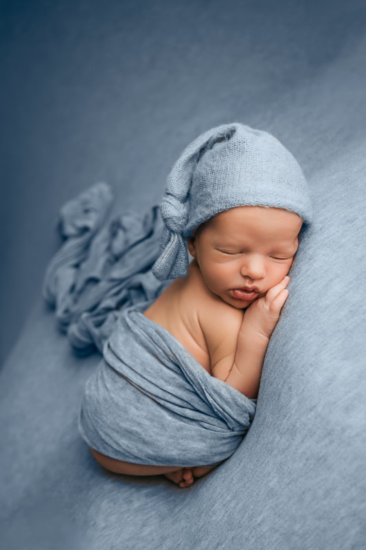 baby boy sleeping on a light blue blanket with a light blue sleep cap on