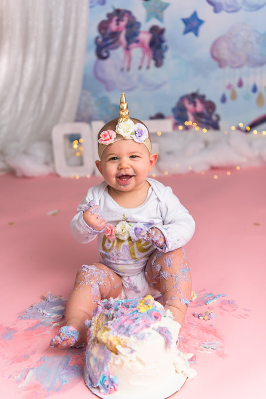Baby in unicorn headband covered in cake