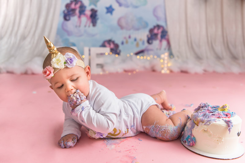 Baby laying on her stomach eating unicorn cake
