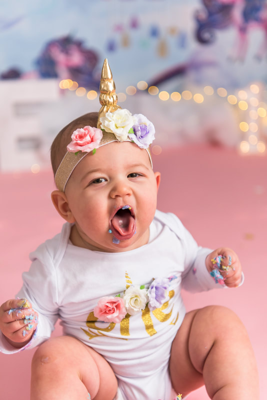 Baby sticking out tongue covered in cake