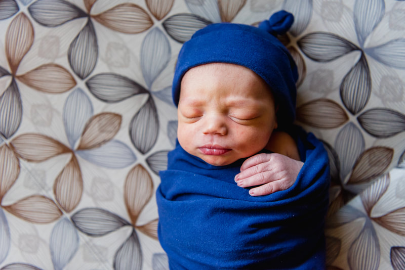 Baby boy wrapped in blue swaddle on hospital bench