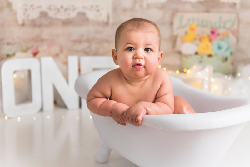 Baby hanging on side of bath tub