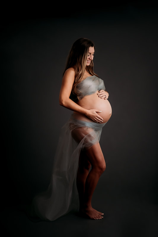Fine art studio maternty photo mom wrapped in fabric showing off her baby bump