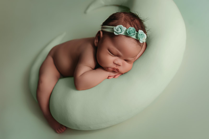 baby girl wearing a teal headband laying on a teal moon