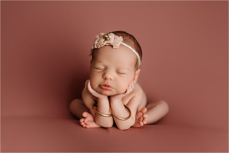 Baby in froggy pose for newborn session on pink backdrop