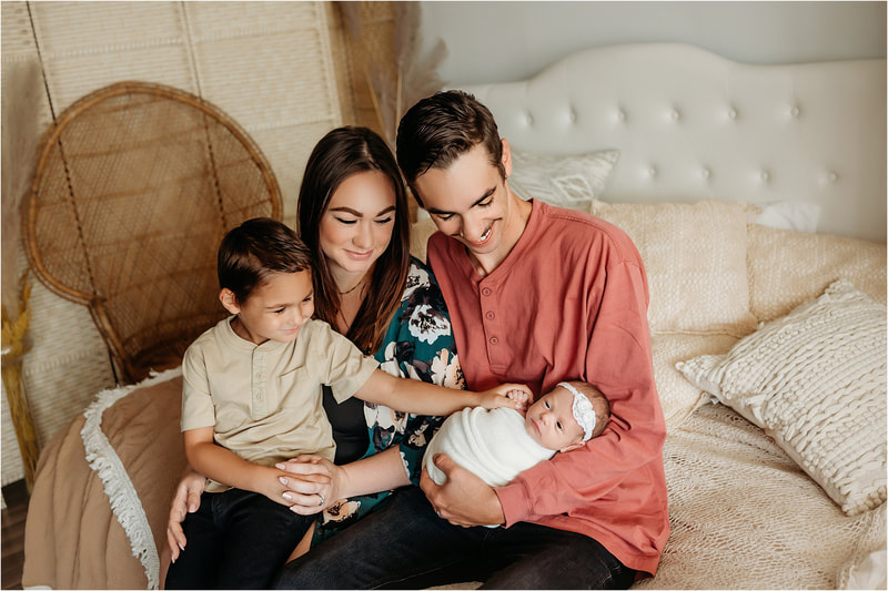 Family snuggling their newborn in a studio phtoography session